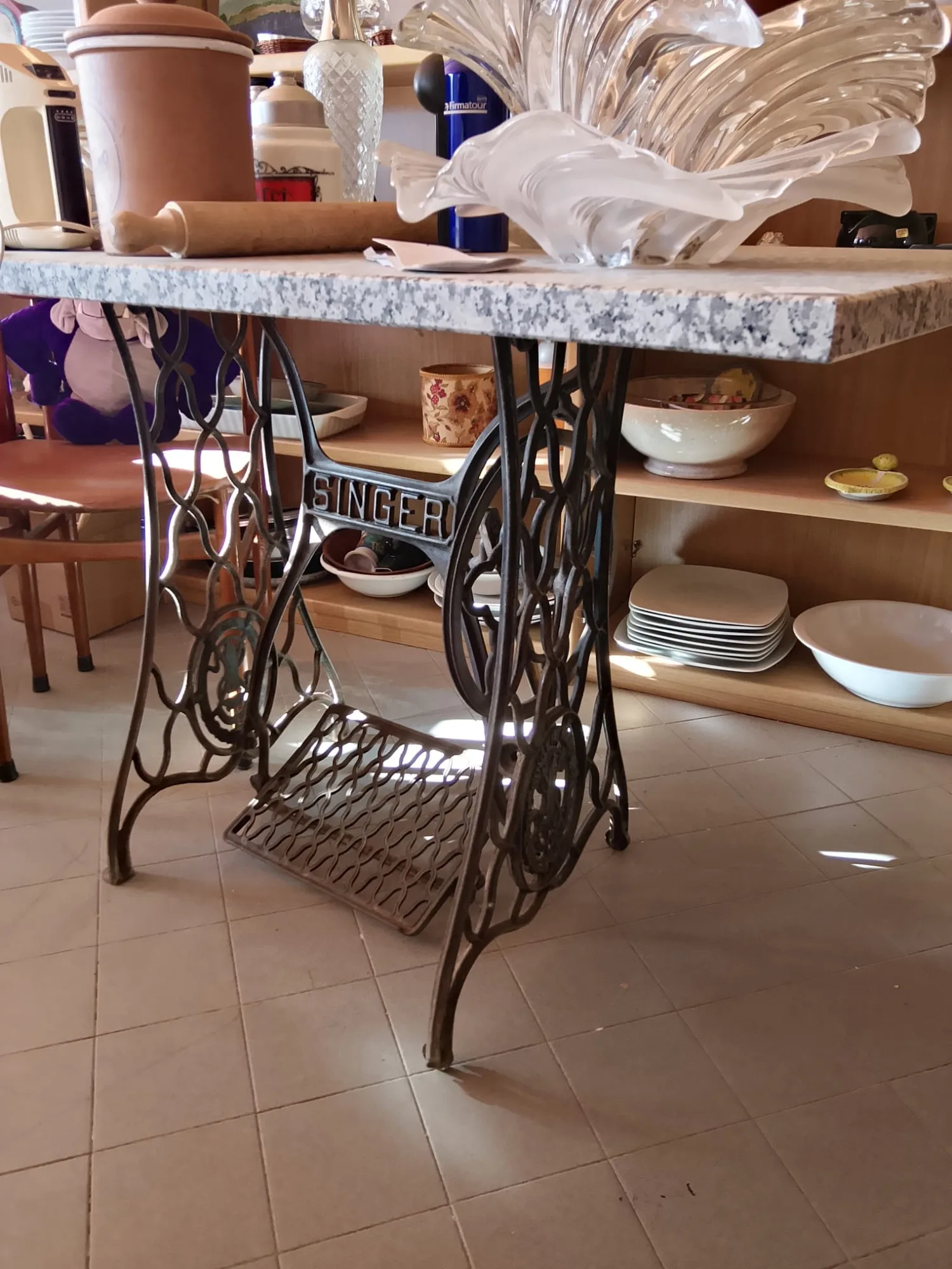 Tavolo con piano in granito appoggiato su base in ghisa di macchina da cucire Singer