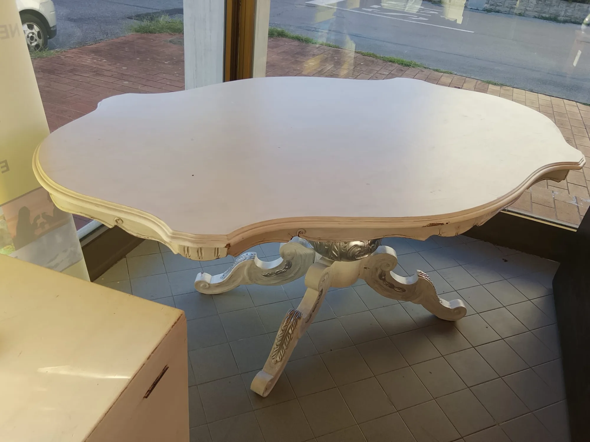 Tavolo ovale laccato avorio con bordo sagomato e base centrale intagliata