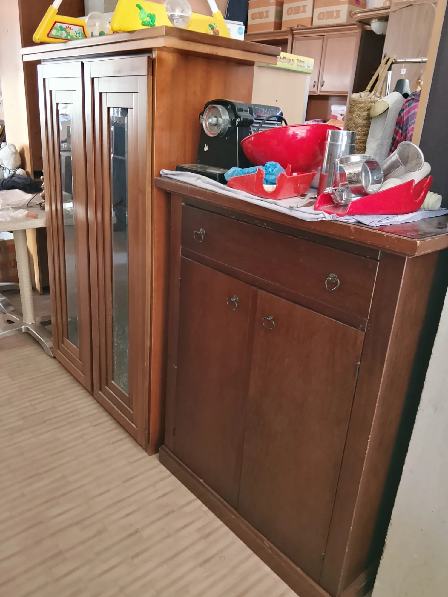 Credenza in ciliegio con cassetto, ante e maniglie ad anello, accanto a una vetrina a due ante