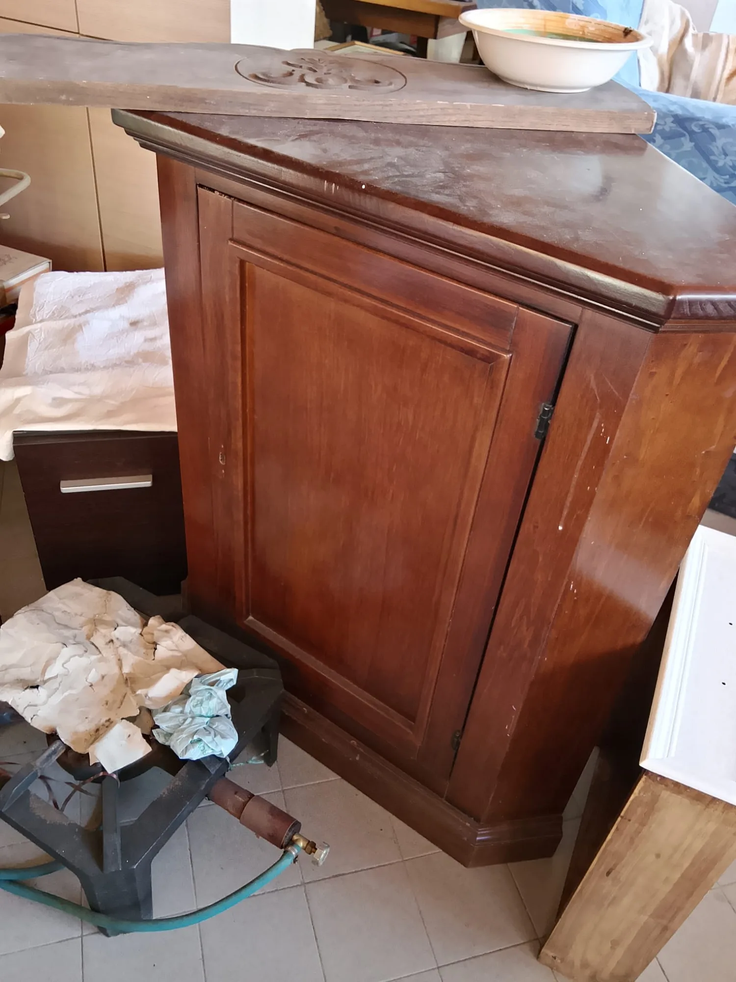 Mobile in legno lucido con anta a pannello e piano intagliato appoggiato sopra, prima del restauro